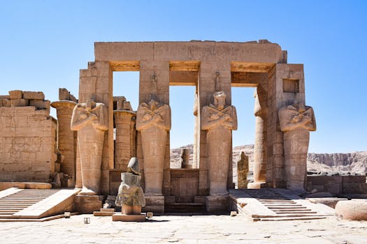 Explore the grand ancient statues and ruins of the Ramesseum in Luxor, Egypt, under a clear blue sky.