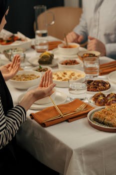 A family prays before enjoying a traditional Ramadan meal together at a beautifully set table.