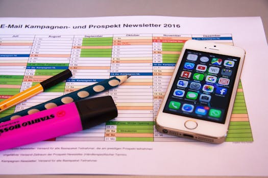 A desk setup featuring a planner, pens, and a smartphone displaying app icons, ideal for productivity.