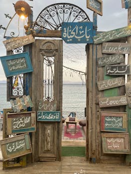 Wooden doorway with signs, leading to a seaside view in Dahab, Egypt.