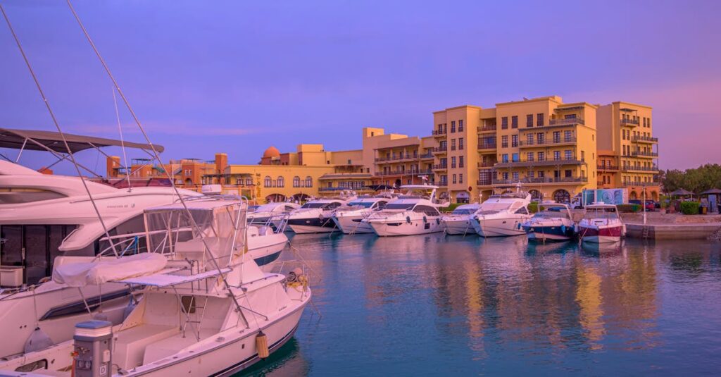 A serene view of luxury yachts docked at Hurghada Marina during sunset, showcasing vibrant architecture.