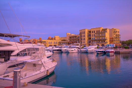 A serene view of luxury yachts docked at Hurghada Marina during sunset, showcasing vibrant architecture.