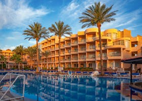 Elegant hotel with palm trees and poolside in Hurghada, Egypt during a sunny day.