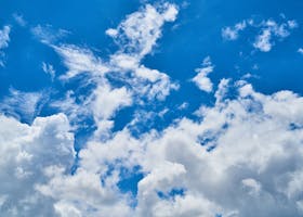 Vibrant cumulus clouds scattered across a clear blue sky, highlighting a perfect day.