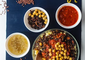 A top view of traditional Egyptian Koshari with ingredients on display, showcasing diverse textures and colors.