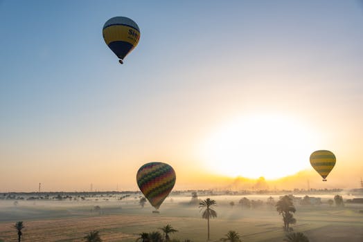 Hot air balloons soar above a misty landscape at sunrise, creating a serene and picturesque scene.